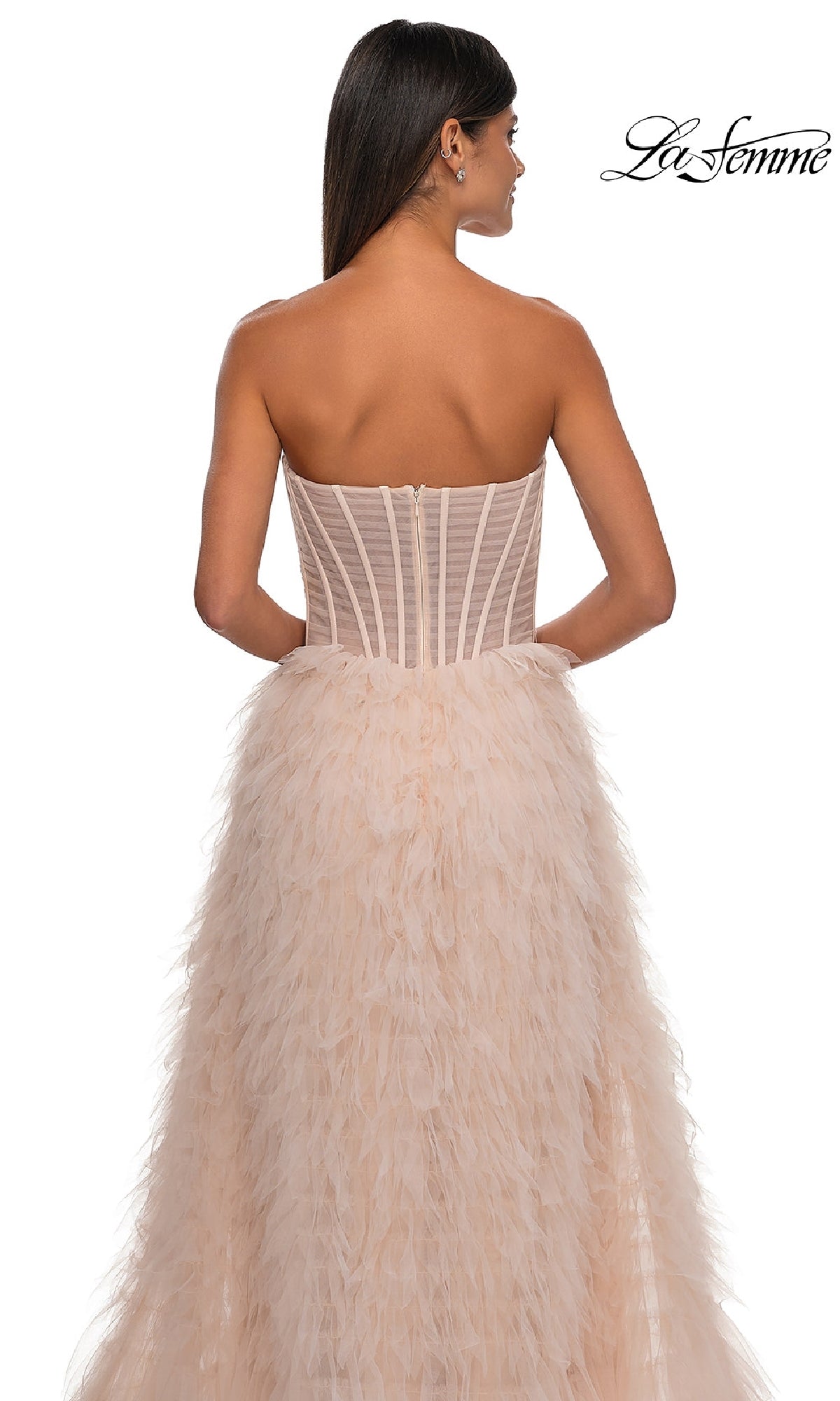 Woman wearing the Strapless Ruffled Prom Ball Gown: La Femme 32528, shown from the back with a nude corset bodice and ruffled skirt, against a white background featuring the